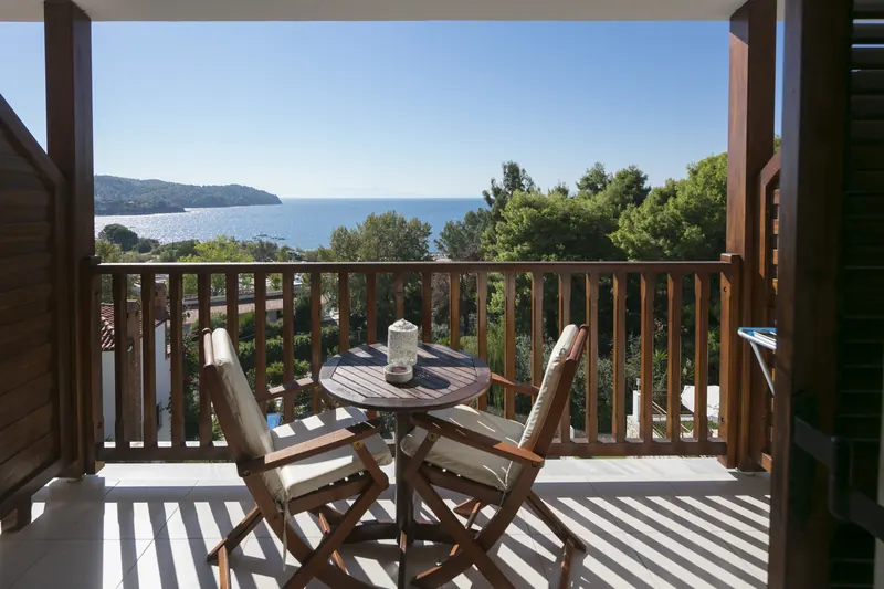 Un tavolo sul balcone con il mare oltre i pini